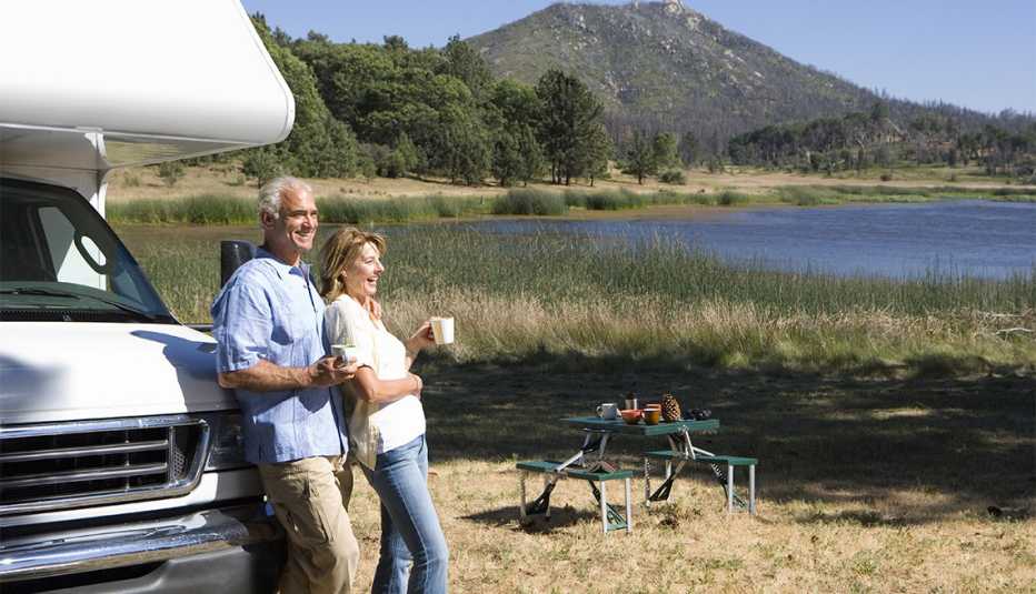 couple relaxing in countryside by lake on motor home vacation