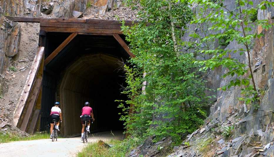 two people riding bikes on a rails to trails bike trail in front of a tunnel