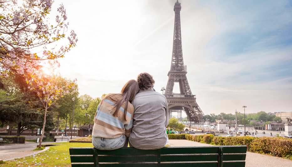 a couple sitting on a park bench overlooking the Eiffel Tower
