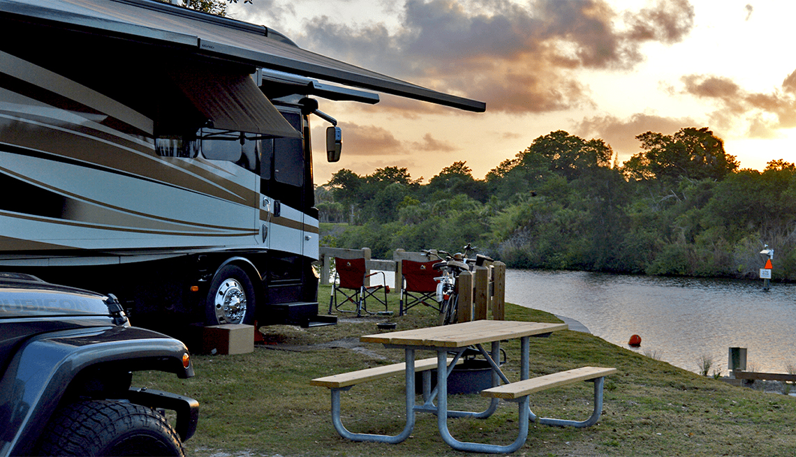 An RV near a lake with outdoor seating at Phipps Parks Florida