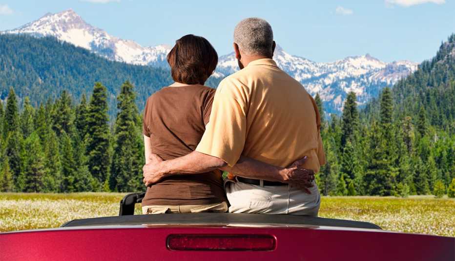 couple sitting in convertible looking at mountains 