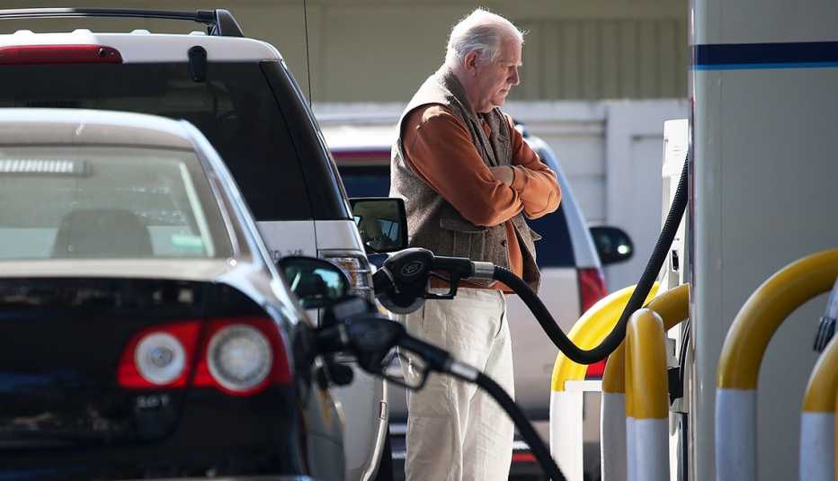 A customer stands with folded arms, watching the price gauge as he pumps gasoline into his car during a price surge 