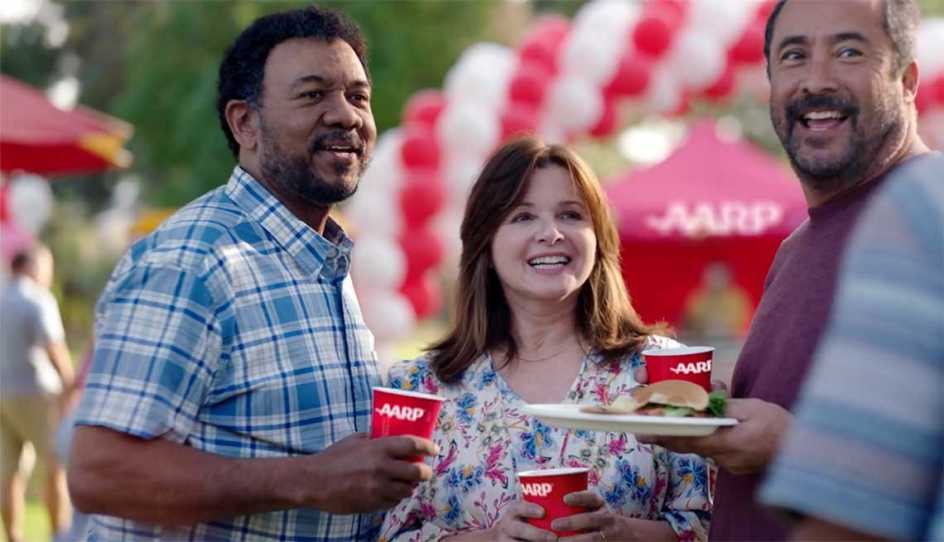 three smiling people outside at AARP event with AARP red cups