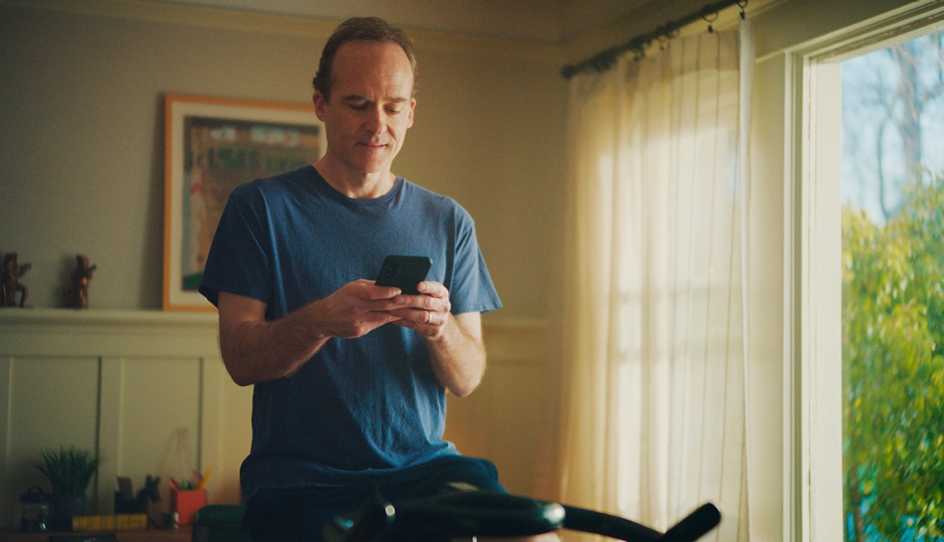 man on exercise bike looking at cell phone