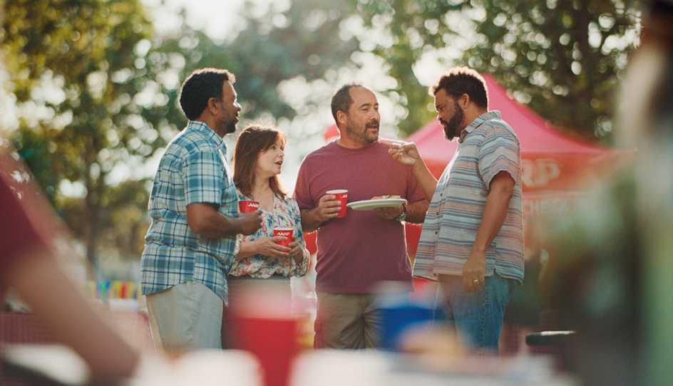 three men and a woman holding red cups outside at BBQ