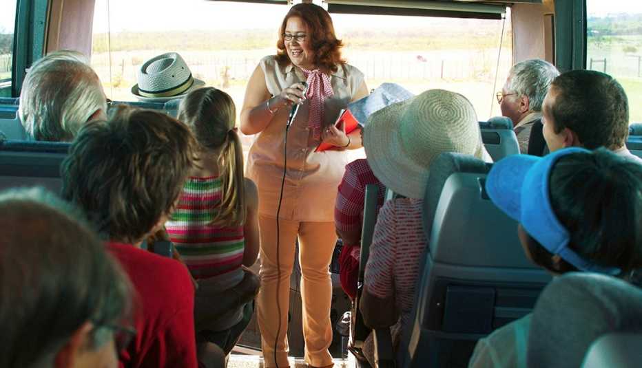 a female tour guide talks to a bus full of people