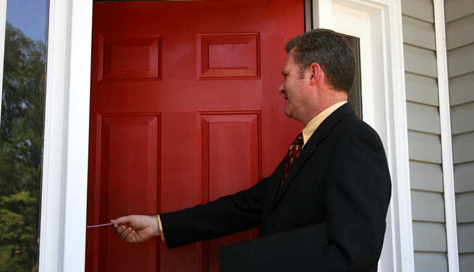 a smiling door to door salesman hands someone a business card
