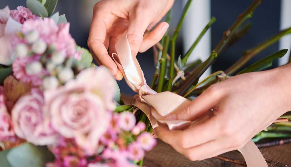 a floral designer ties a ribbon on roses