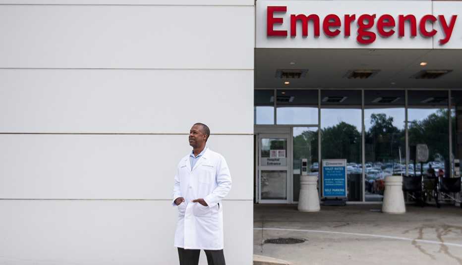 doctor carl allamby poses outside the glass doors of a hospital emergency room
