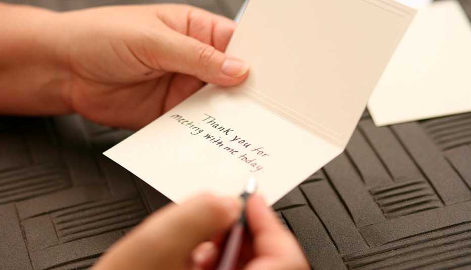 A person is filling out a thank you card