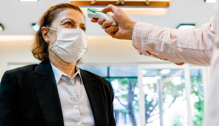 A woman gets her temperature checked while wearing a mask