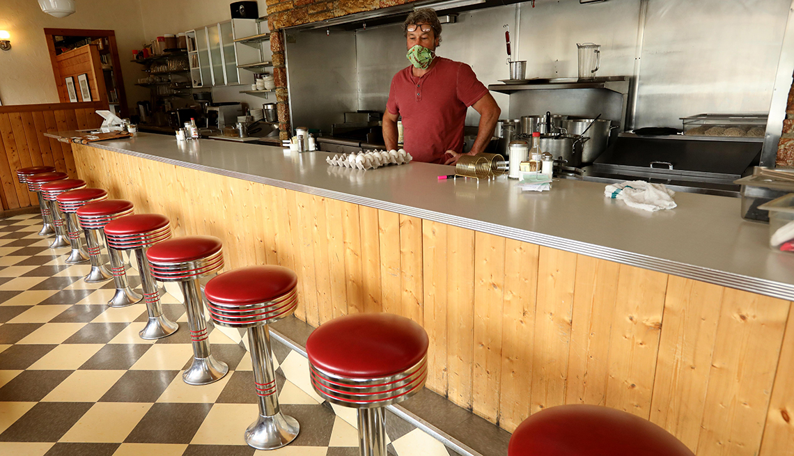 A worker stands behind the counter at an empty restaurant