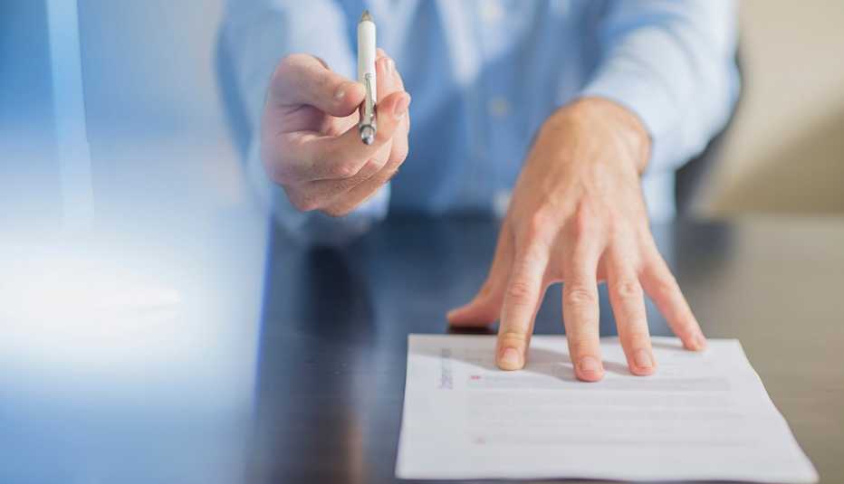 a person holds out a pen and a paper to sign