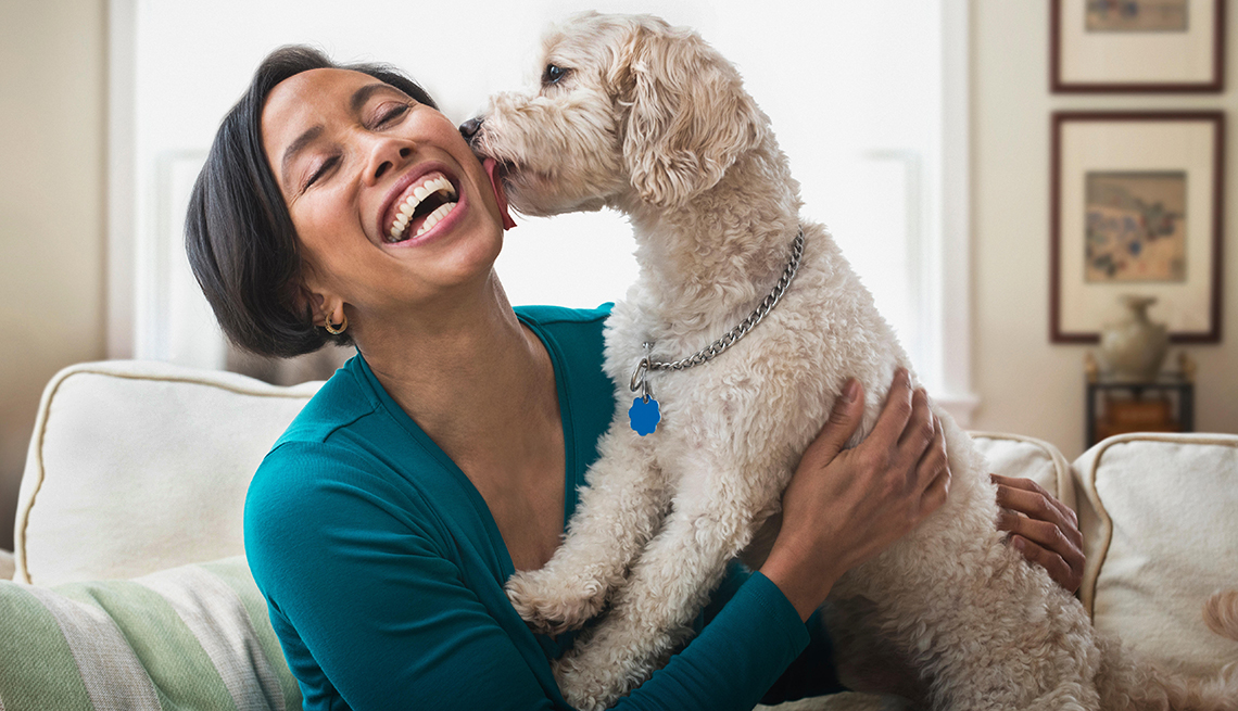 a woman gets a kiss from a dog she's pet boarding for the summer