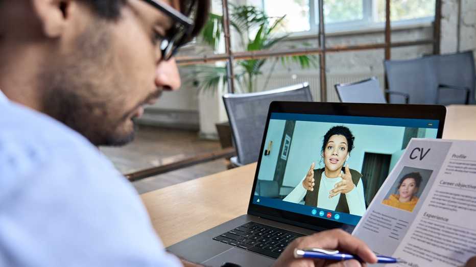 a woman participates in an online interview with a man who is looking at her cv