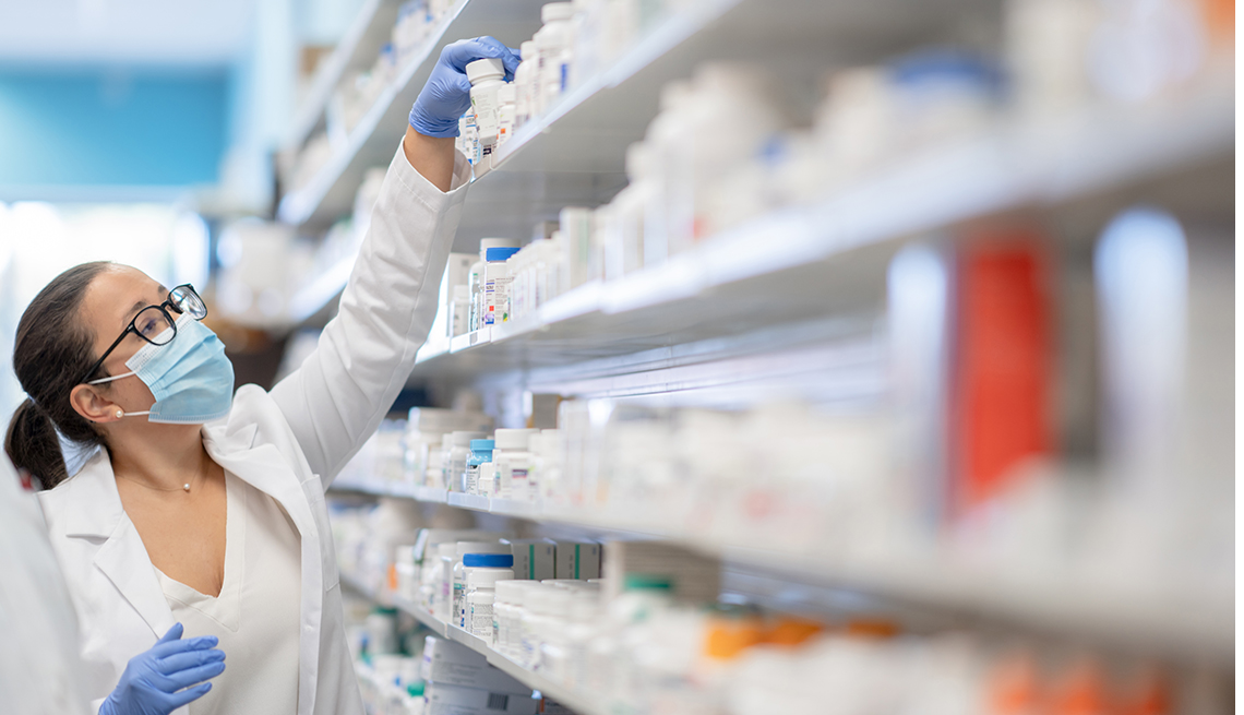 female pharmacy tech reaches for a bottle of medicine