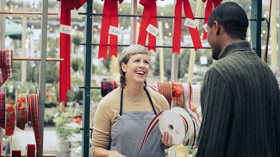 a seasonal worker at a wrapping station talks to a customer