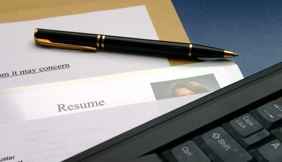 A resume and cover letter on a desk with a computer and pen