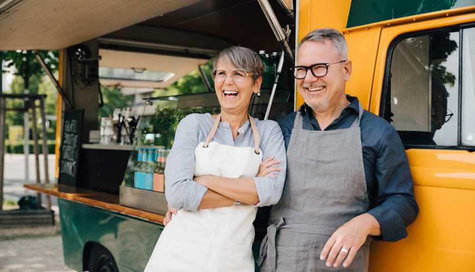A couple stands next to a yellow food truck