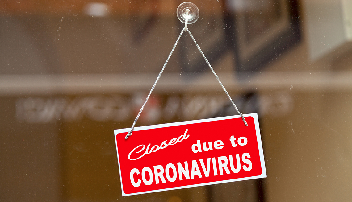 A red sign hangs from a door that says closed due to coronavirus