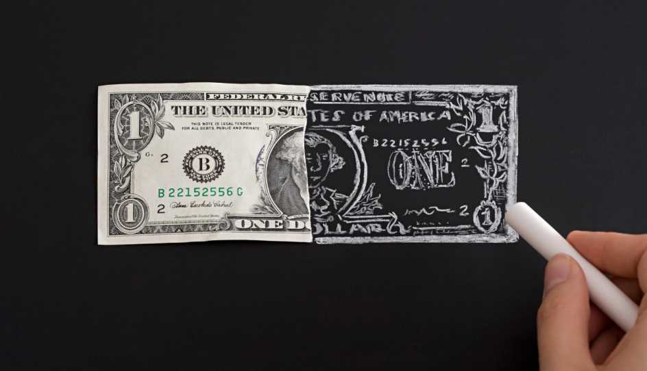 Un dólar con la mitad dibujada con tiza sobre fondo negro.