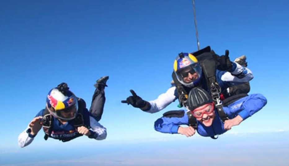Un paracaidista solitario a la par de dos paracaidistas tándem en caída libre