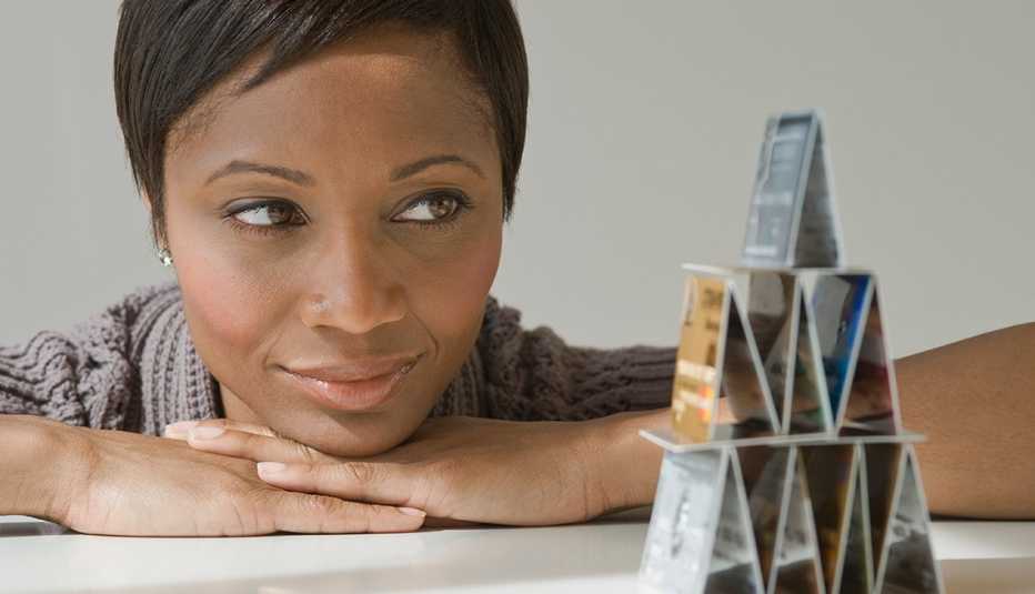 Mujer mirando una pirámide de hecha con tarjetas de crédito y aprende de los secretos de estas compañías