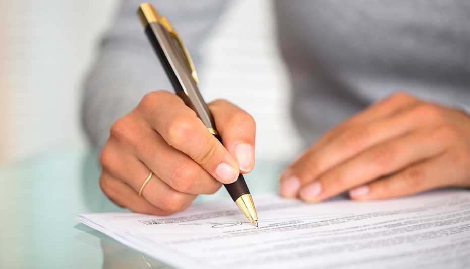 Manos de una mujer firmando un contrato... cuidado cuando eres codeudor de un préstamo