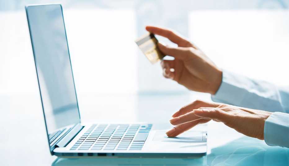 Manos con una tarjeta de crédito frente a un computador - Opciones para eliminar las deudas de tu tarjeta