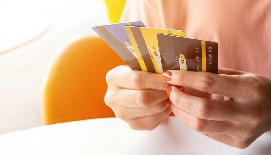 Manos de una mujer con varias tarjetas de crédito en la mano.