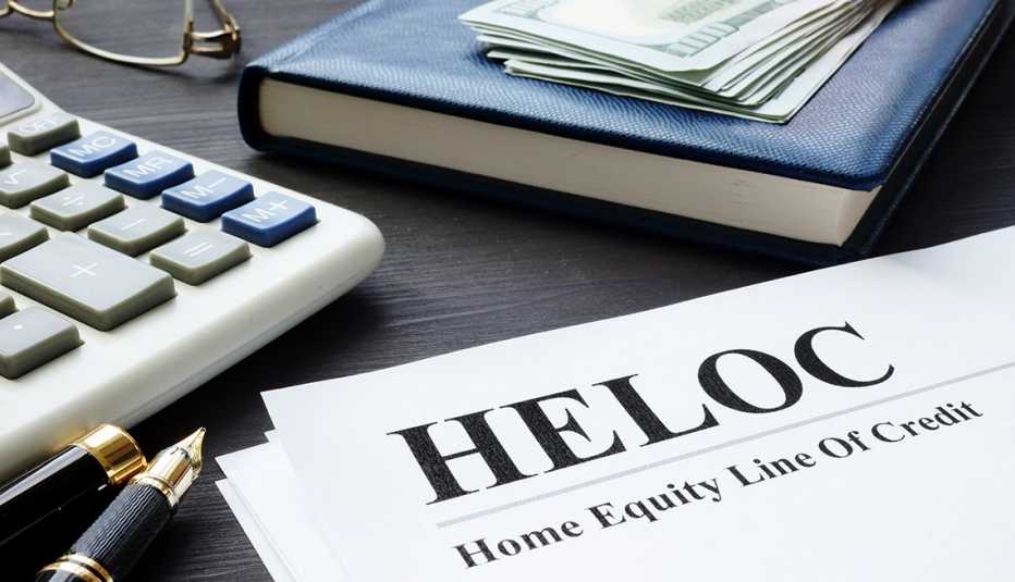 Calculadora, agenda y dinero en efectivo al lado de un formulario que dice línea de crédito con garantía hipotecaria