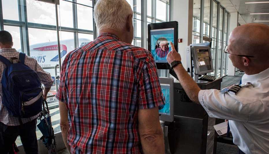 Hombre parado frente a un escáner biométrico de reconocimiento facial en un aeropuerto.