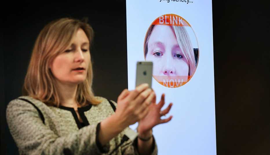 Mujer sostiene un teléfono inteligente para demostrar la tecnología de reconocimiento facial