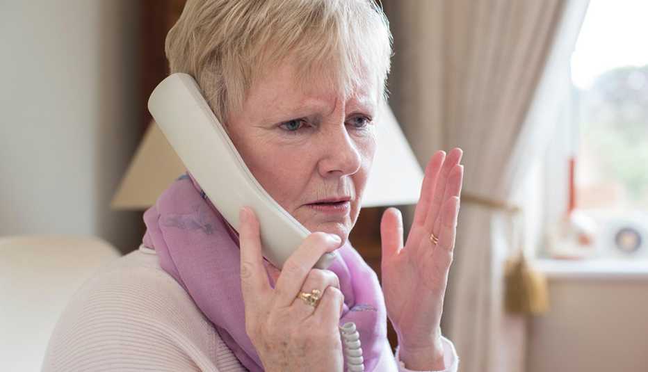 Mujer hablando por un teléfono fijo