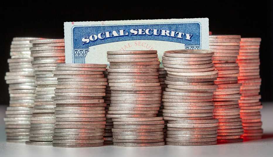 Tarjeta del Seguro Social detrás de varias monedas apiladas.