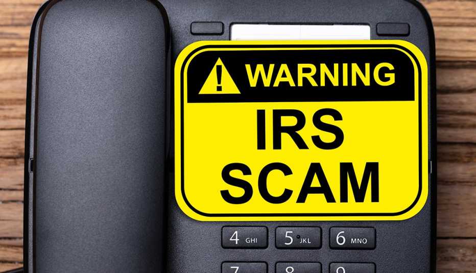 Teléfono fijo con un letrero que dice advertencia fraude del IRS.