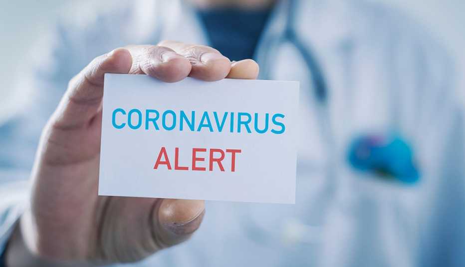 Médico que sostiene una tarjeta que dice alerta de coronavirus.