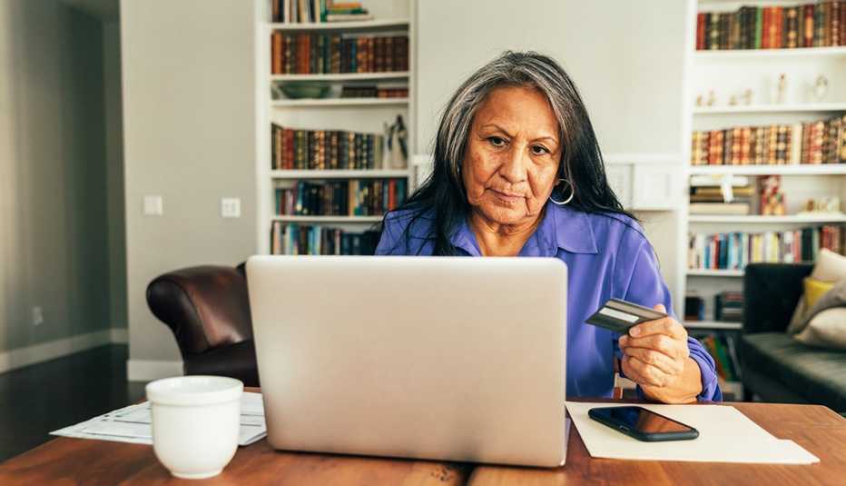 Mujer mayor frente a su computadora en el comedor de su casa.