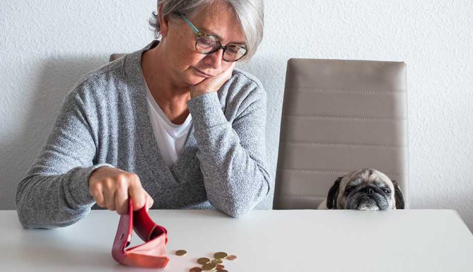 Mujer mirando unas monedas que vacía sobre una mesa.