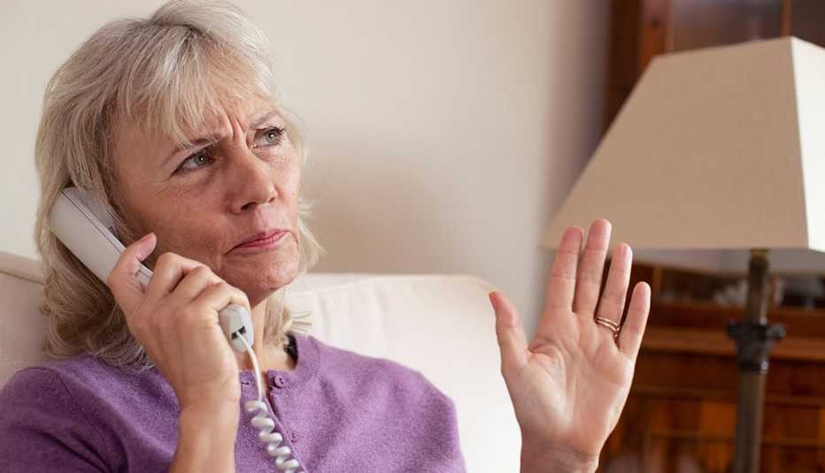 Mujer sosteniendo un auricular de teléfono desde la sala de su casa