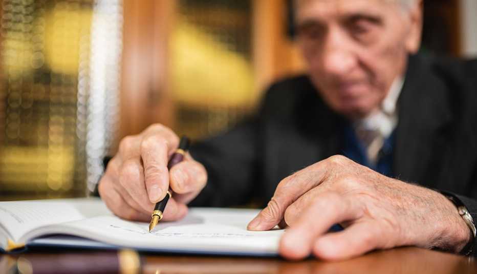 Hombre mayor firmando un documento en una oficina.