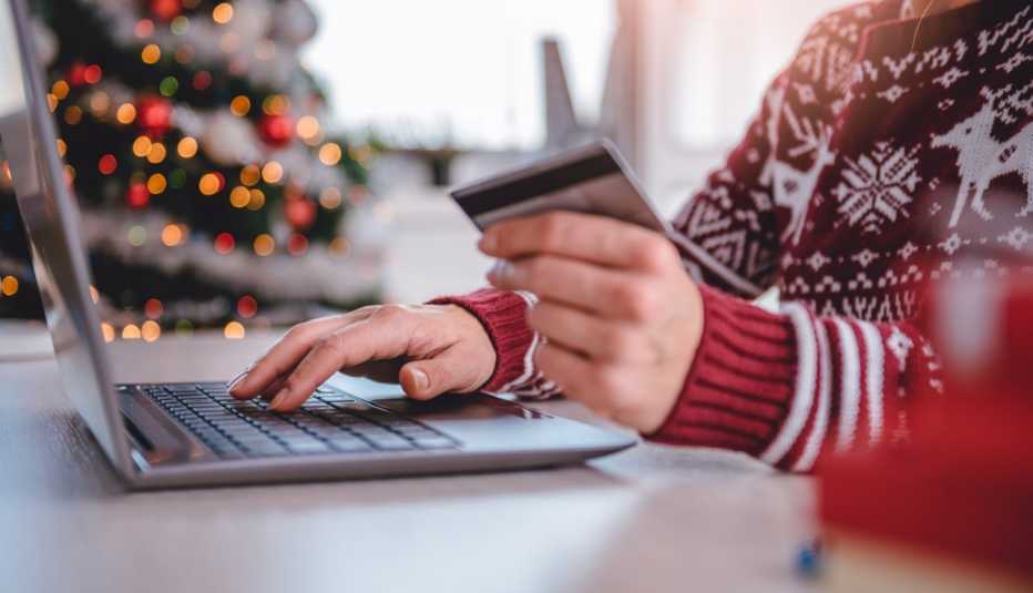 Mujer vestidas con suéter rojo comprando en línea y usando tarjeta de crédito en la oficina del hogar.