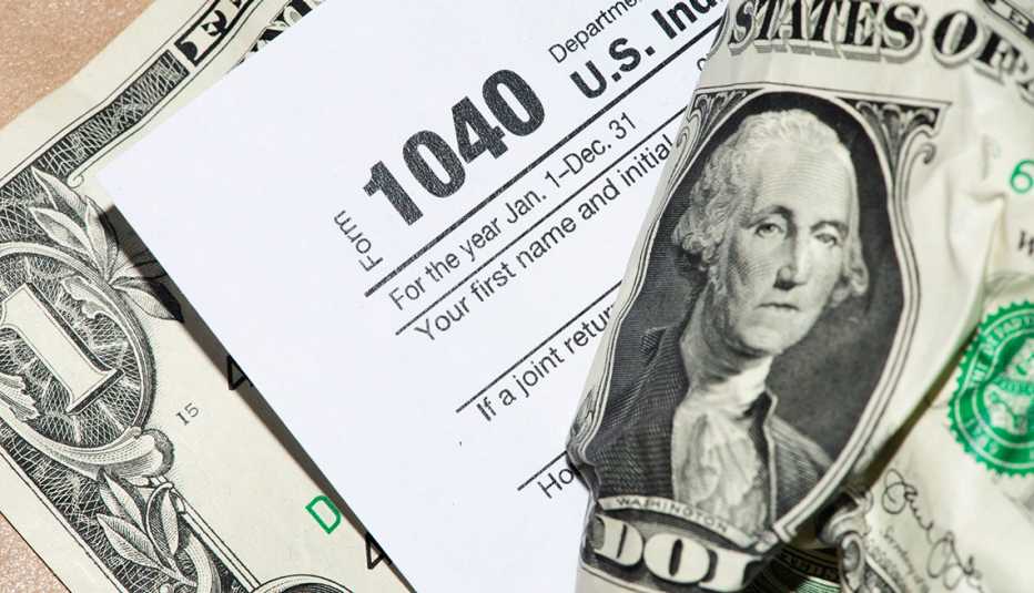 Formulario de impuestos 1040 en medio de billetes de dólar.