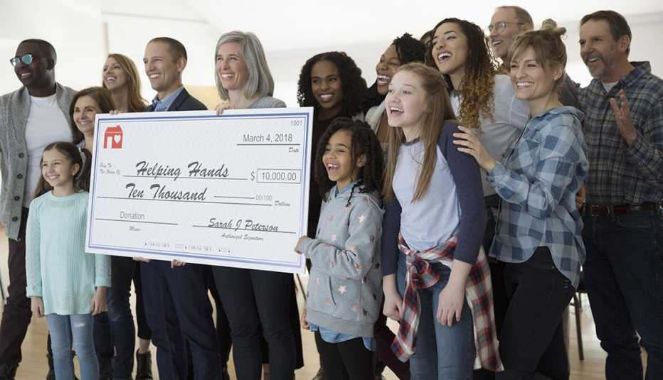 Personas sonriendo y mostrando un cheque gigante de una donación