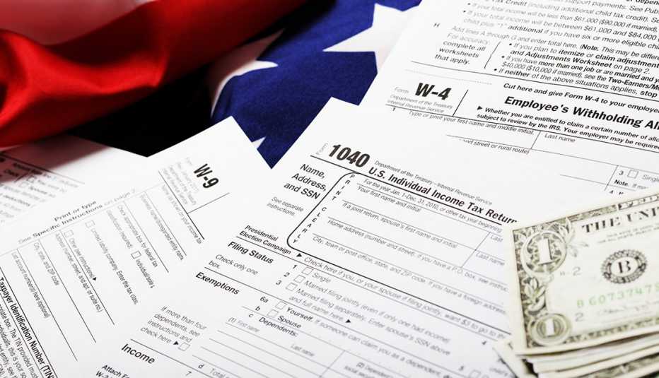 Formularios de impuestos del IRS con unos dólares al lado y la bandera de Estados Unidos