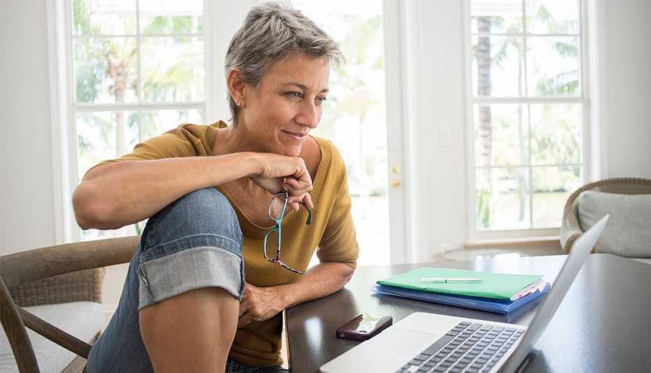Mujer en jeans frente a un computador portátil