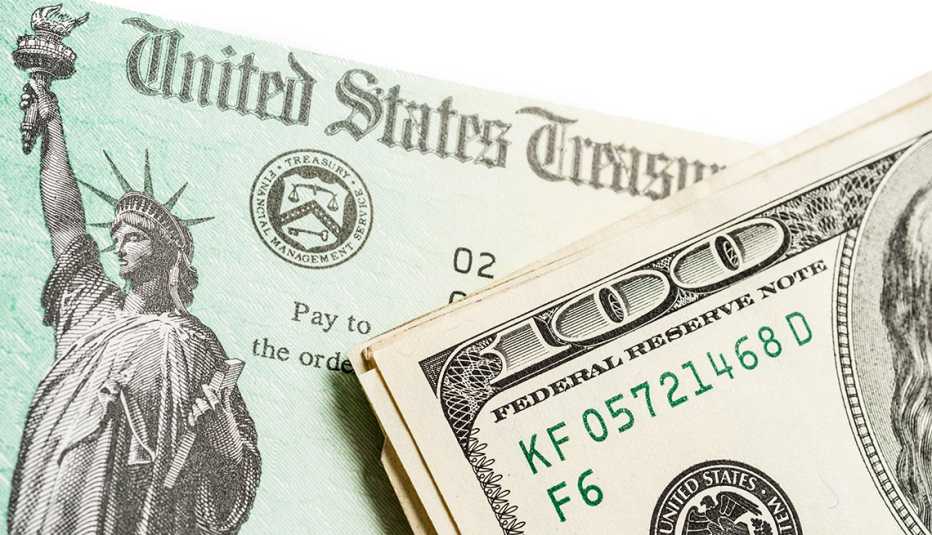 Un cheque del Departamento del Tesoro de Estados Unidos con dinero al lado