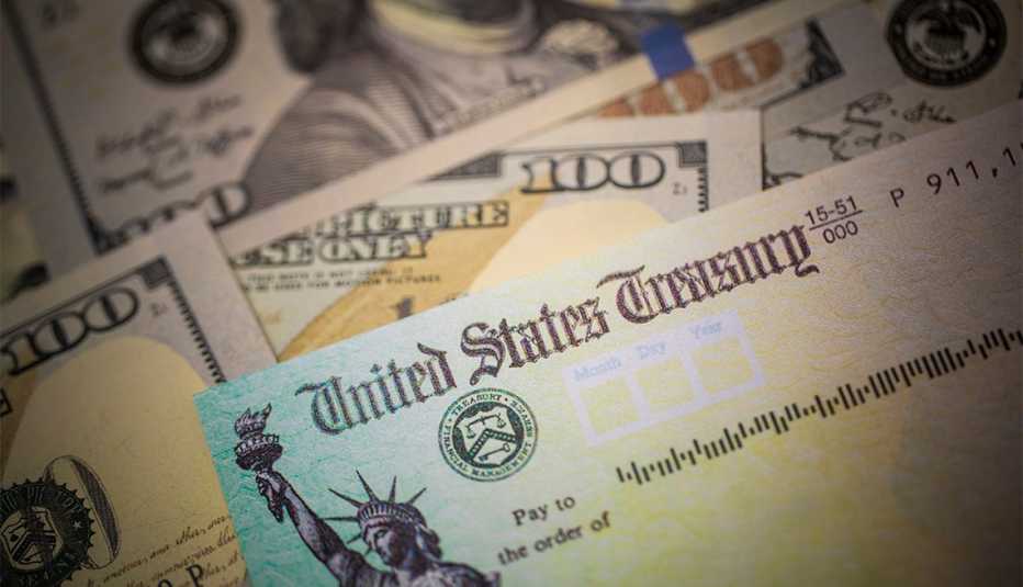 Cheque de estímulo del Departamento del Tesoro de los Estados Unidos encima de billetes de $100 dólares