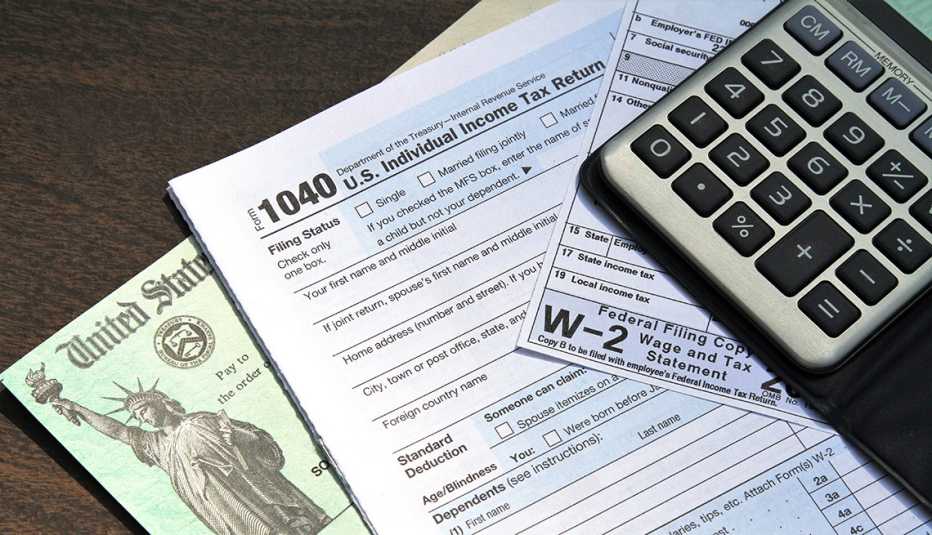 Cheque del Tesoro de Estados Unidos, formulario 1040 y W-2 del IRS, y una calculadora.
