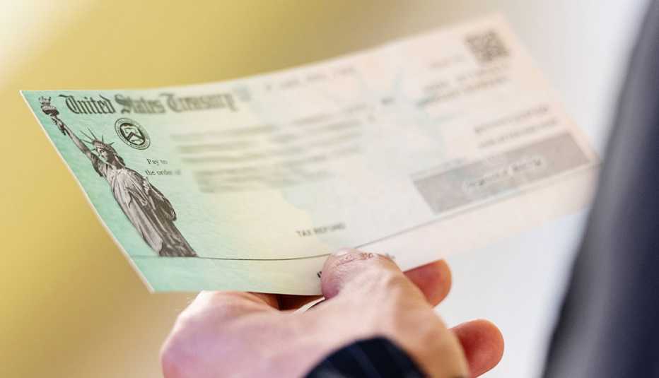 Mano de una persona sostiene un cheque del Departamento del Tesoro de Estados Unidos